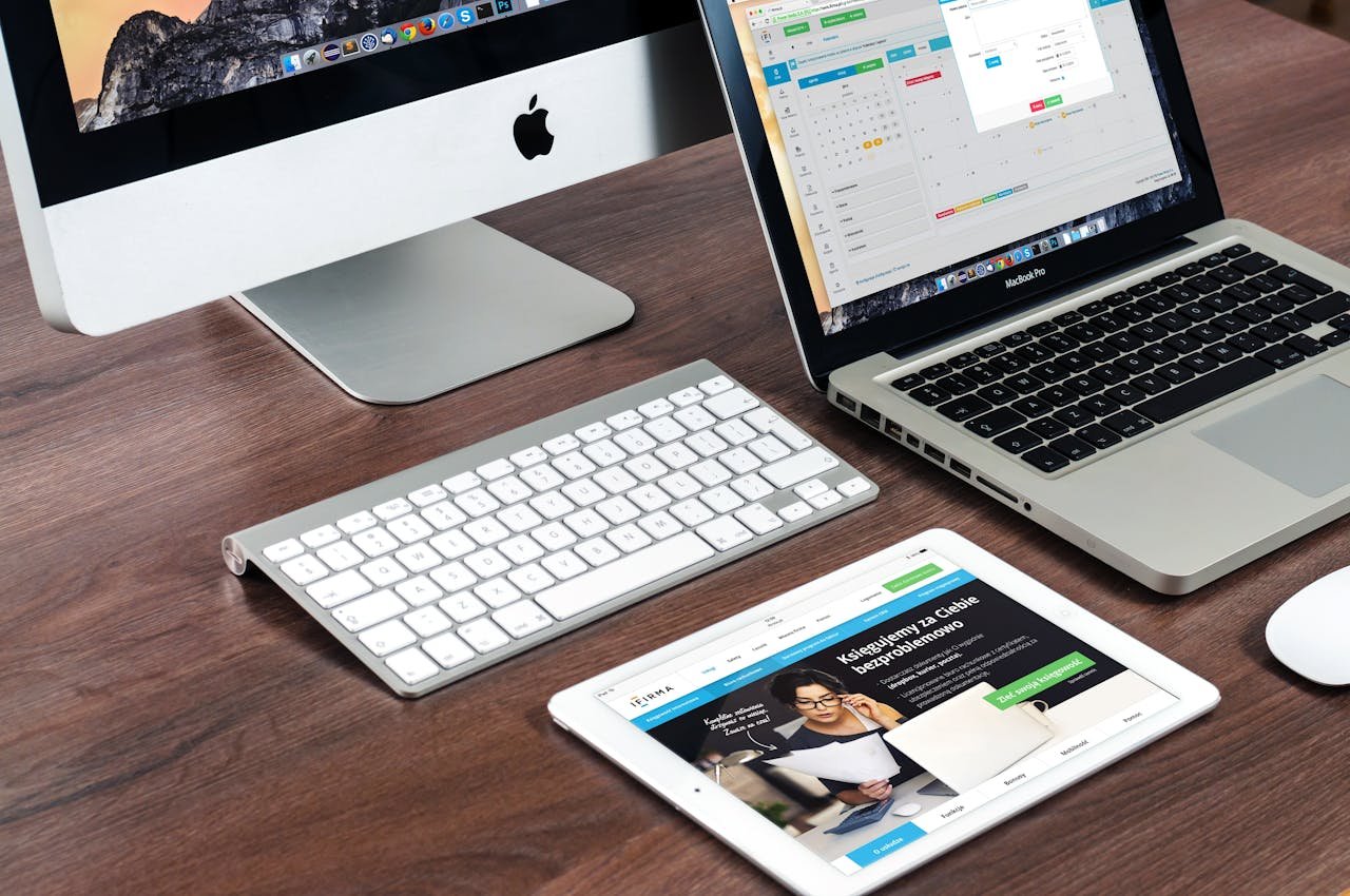 heros-img A sleek office desk setup featuring Apple devices: iMac, MacBook, and iPad.